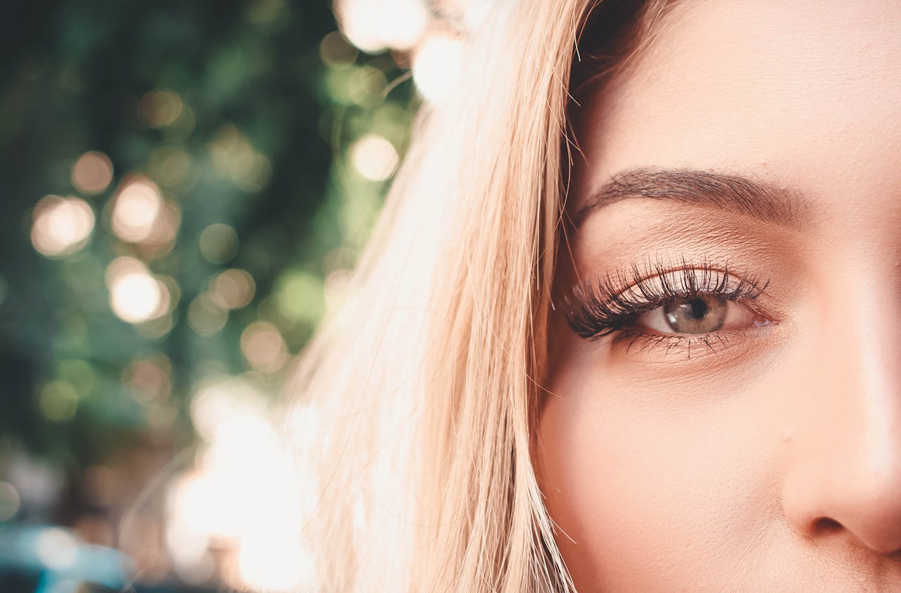 Detailed close-up of a womans eye showcasing long eyelashes and eyebrow outdoors.