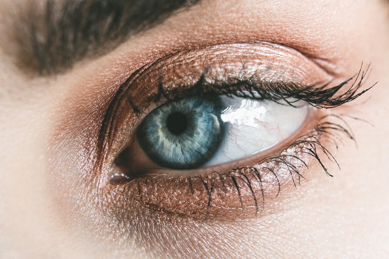 Detailed close-up of a womans blue eye, showcasing makeup and eyelashes.