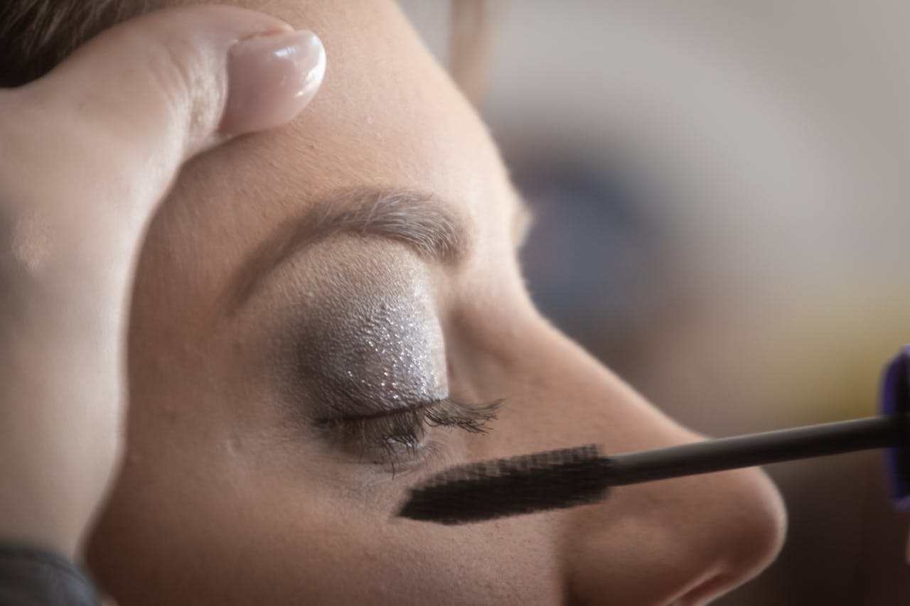 A womans eyelid is delicately painted with glamorous shimmery eyeshadow and mascara.